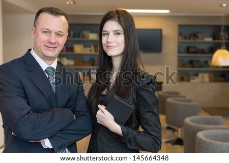 A smiling girl with notepad and a man in suits standing in the room