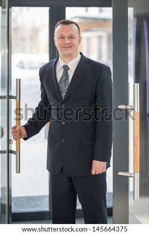 A businessman in a suit enters the glass door
