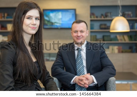 A girl with a man in business suits sitting on chairs
