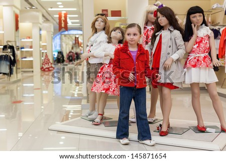 MOSCOW - MAR 18: Little Jeanette 6 years trying on clothes together with mannequins in the large store children clothes Jakimanka on March 18, 2012 in Moscow, Russia.