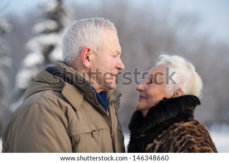 Elderly couple in winter park looking fondly at each other