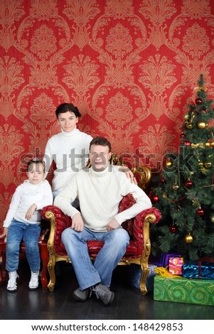Happy family in white sweaters and jeans near Christmas tree at home.