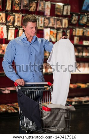A man with a clothes in the cart in lingerie store