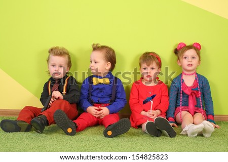 Two boys and two girls in bright clothes sitting at the bright wall