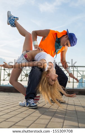 Young couple dancing modern dance in beautiful pose in the street