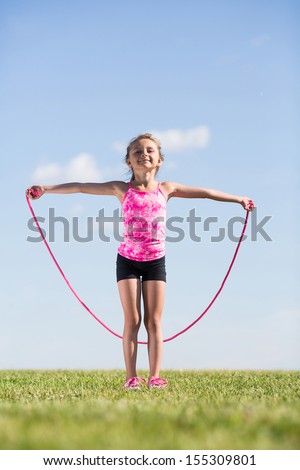 Little girl on the nature of the jumps with a skipping rope
