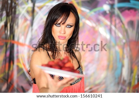 Girl with a plate of strawberries in hand in the studio