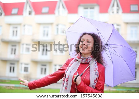 A young woman in a red jacket with a purple umbrella on the street