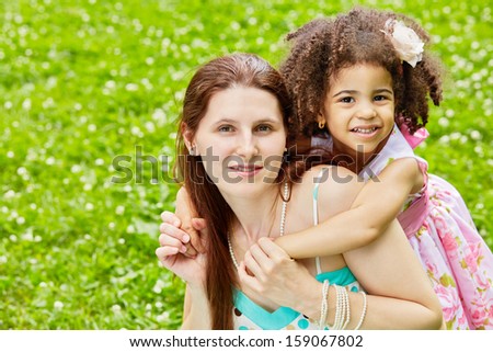 Little girl embraces her mother from behind, mother holds daughter hands
