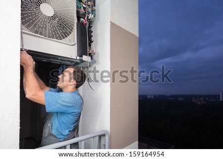 A worker sets split system air conditioner in the evening