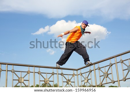 A man stands on a thin fence during the breakdancing