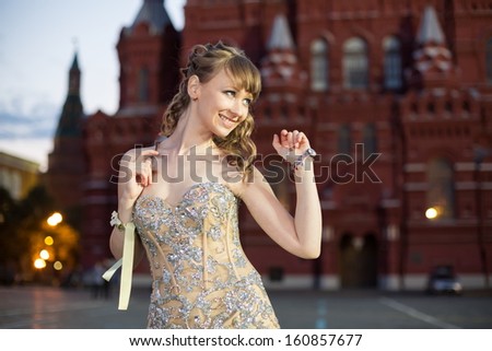 A smiling girl in a beautiful dress on Red Square near the Historical Museum