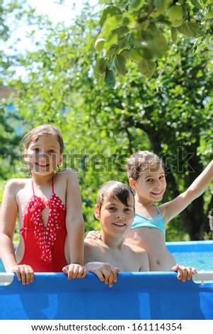 Three happy kids having fun in swimming pool on the courtyard outdoor