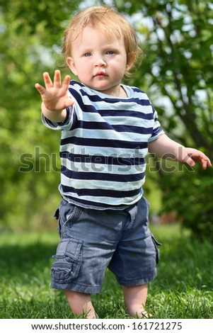 Little Barefoot Boy In Shorts Stands On Green Grass And Reaches Out At ...