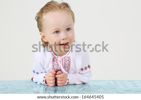 Little boy in Russian national costume and big map on white background.