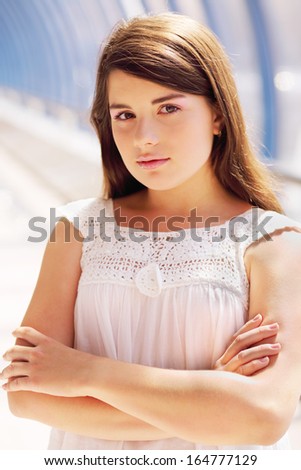 Smiling girl in white blouse stands in long blue gallery and looks at camera.