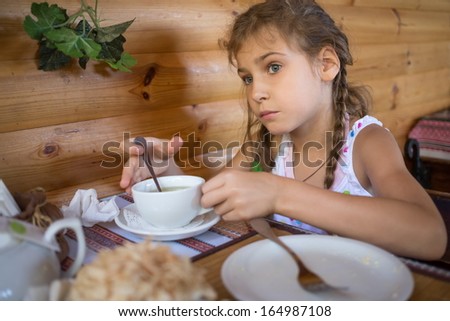 Little girl sitting in a cafe at the table with an empty plate