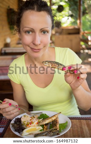 Smiling girl sitting in a cafe at the table with food of rice and fish