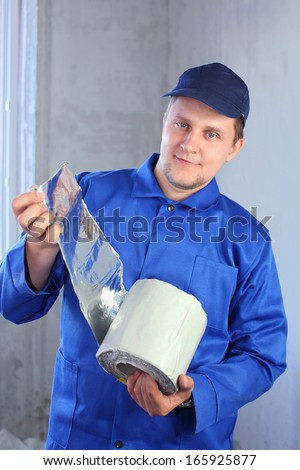 A man in work clothes holding a roll of foiled insulation for windows