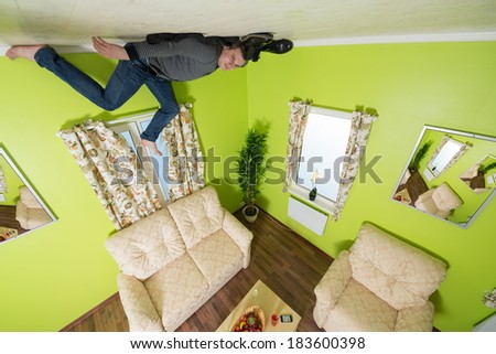 Man in jeans lying on the ceiling under the sofa without shoes and socks