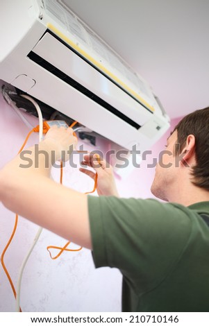 Young worker inserts an orange water pump in air conditioning