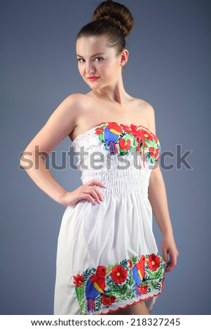 Beautiful sexy young woman in a white dress with colored embroidery