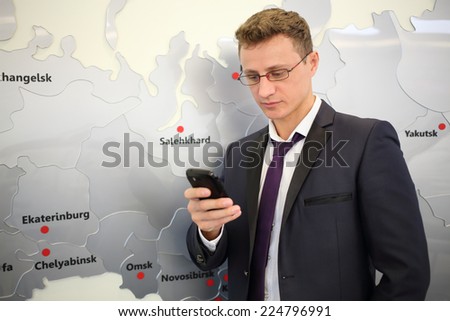 Portrait of businessman with phone leaning against wall with map