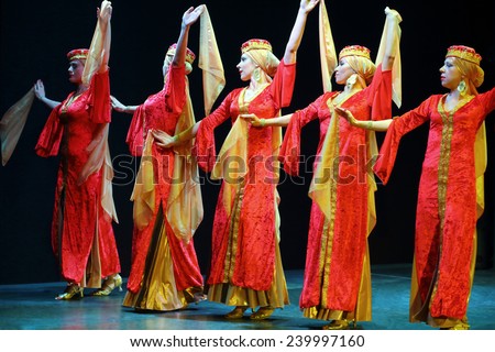 MOSCOW, RUSSIA - APR 26, 2014: Beautiful women in red dress dancing with scarves in a line on stage at the art cafe Durov
