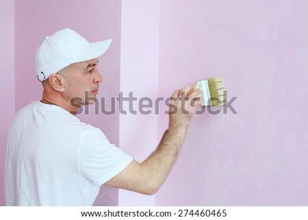 Construction finisher in white clothes covers the walls pink decorative plaster