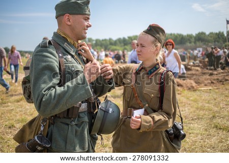 NELIDOVO, RUSSIA- JULY 12, 2014: Soviet soldier girl straightens uniform of a German soldier at the Battlefield 2014