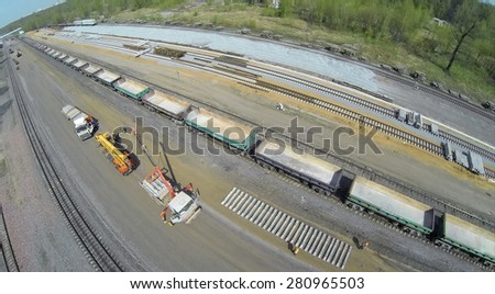 RUSSIA, MOSCOW - APR 30, 2014: Workers unload sleepers from trucks with cranes on building site of railroad beltway widening for opening of passenger traffic. Aerial view