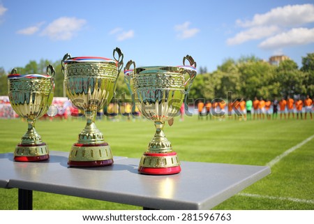 MOSCOW - MAY 14, 2014: Three Cups for winners of the International football tournament Cup of Victory in front of a football field and teams at the Spartakovets stadium in Moscow