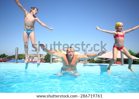 Boy and girl with grandfather jumping into a pool of water