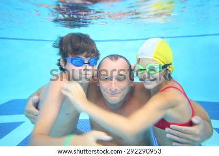 Portrait of grandfather with boy and girl under water in the swimming pool