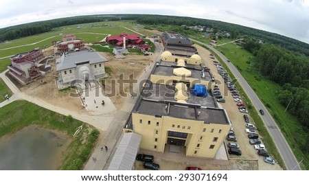 RUSSIA, BOROVSK - 13 JUN, 2014: People walk by cultural complex Etnomir with many cars on large parking at summer day. Aerial view. Photo with noise from action camera