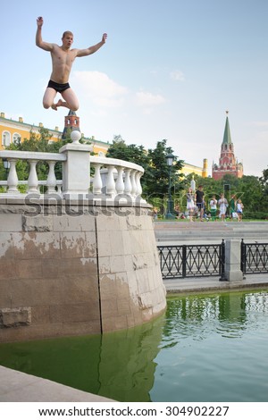 MOSCOW - AUG 12, 2014: A young man jumping in the water at the Manege Square