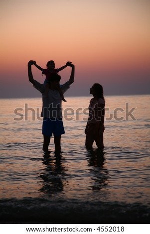 Family in sea alongshore on sunset