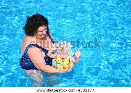 The grandmother plays with the granddaughter in pool
