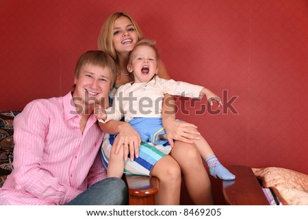 young family laughing in armchair in red room