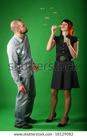 Girl with red hair blows soap bubbles, and guy looks at it