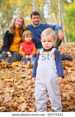 Little boy with family in forest in autumn