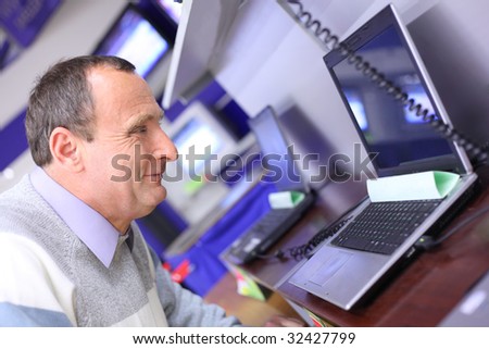 elderly man in shop looks at laptop