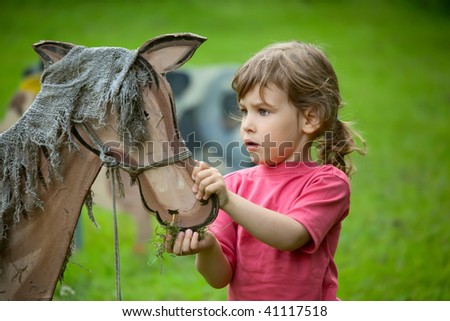 The girl feeds a wooden horse