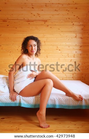 beautiful hot woman sitting on bed in cozy wooden room