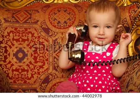 Little girl in red dress talking vintage phone. Interior in retro style. Horizontal format. Close up.