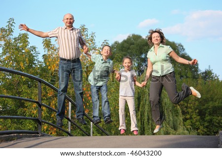joyful family with two children is jumping on a bridge. family is handies.