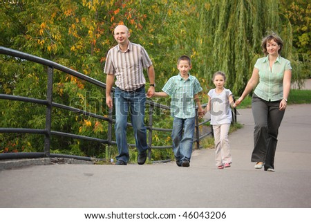 family with two children is handies on a bridge and walking