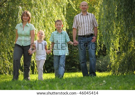 dad, mom, son and daughter is walking in early fall park.