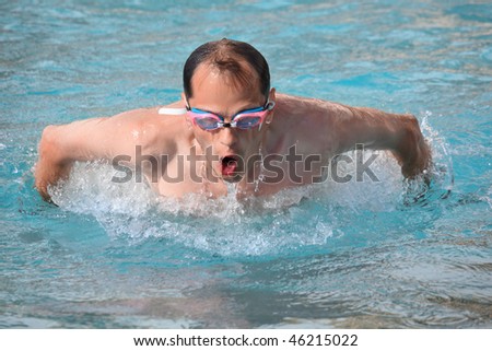 young man in waters sport goggles swimming in pool, jumped out of water