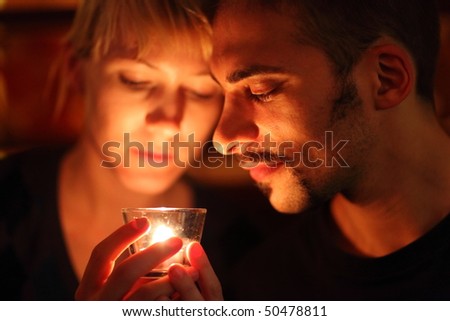 man and woman keeping glass candle. focus on man\'s left eye.
